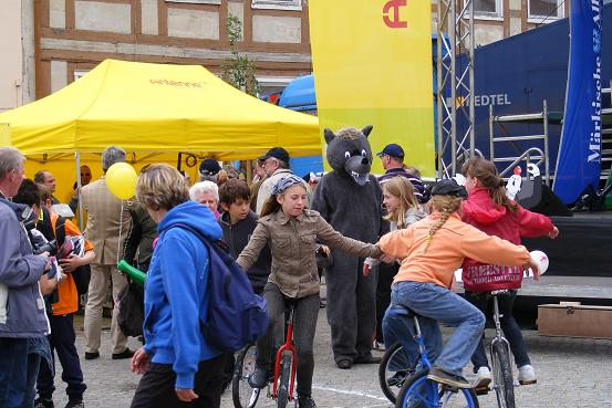 Pritzwalker Wappenwolf hinter Mädchen auf Einrädern auf dem Wusterhausener Marktplatz nach Etappe 3 der Tour-de-Prignitz 2010 von Pritzwalk nach Wusterhausen